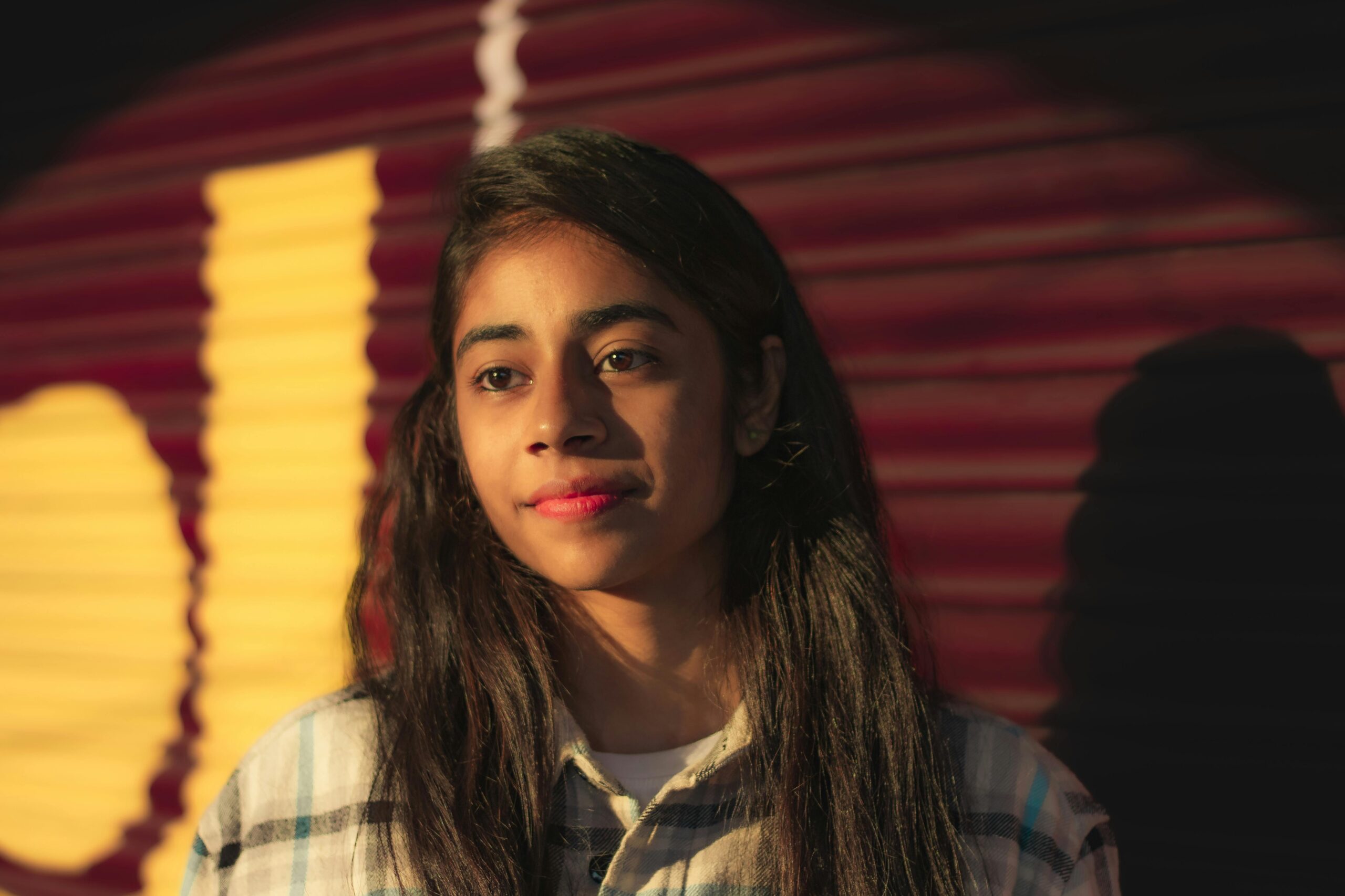 Portrait of a pensive teenager with sunlight casting vibrant shadows.